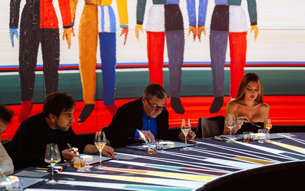 Guests dining at IMAGINARY ART show, KRASOTA Dubai, with colorful mural backdrop.