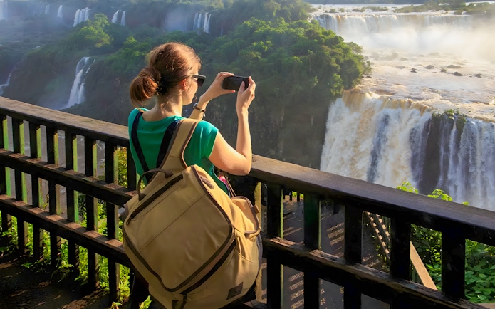 Tourist taking photo at Iguazú Falls viewing platform, Brazilian side.