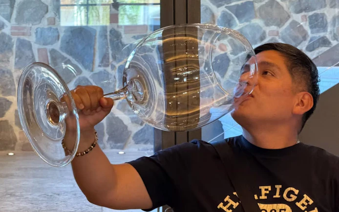 Man enjoying wine tasting with oversized glass in Tuscany winery.