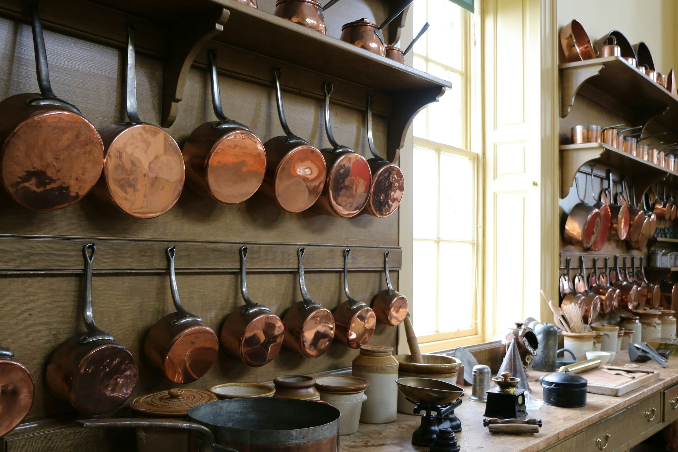 Historic kitchen with vintage utensils and cookware on display in a traditional setting.