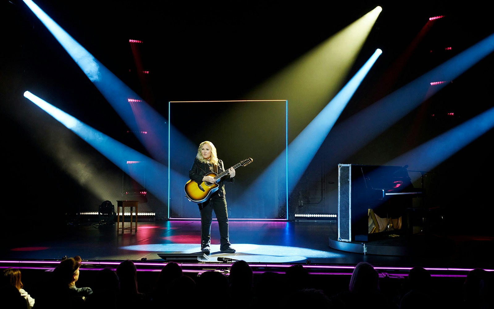 Musician performing on stage with guitar under spotlight during "Melissa Etheridge: My Window" show.