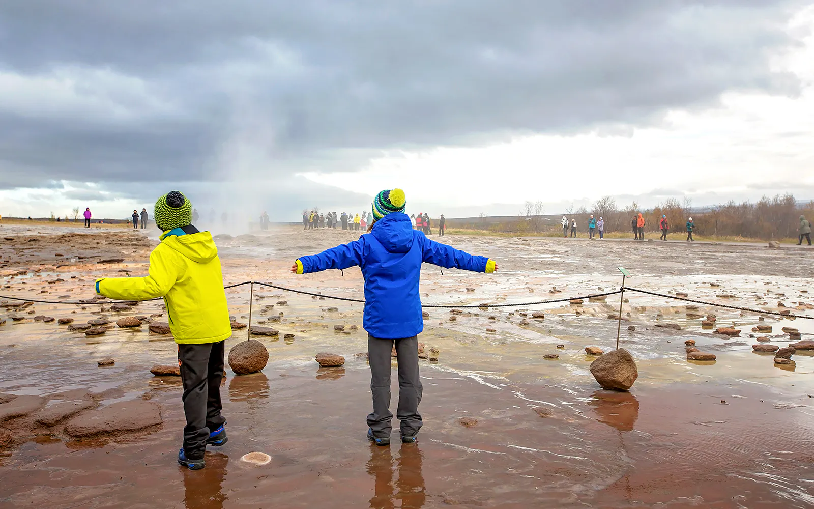 Children observing geyser eruption on Golden Circle tour, Iceland.