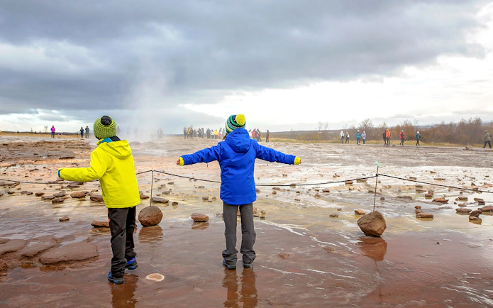Children observing geyser eruption on Golden Circle tour, Iceland.