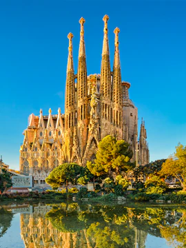 Sagrada Familia in Barcelona, Spain, illuminated during golden hour with surrounding trees and buildings.