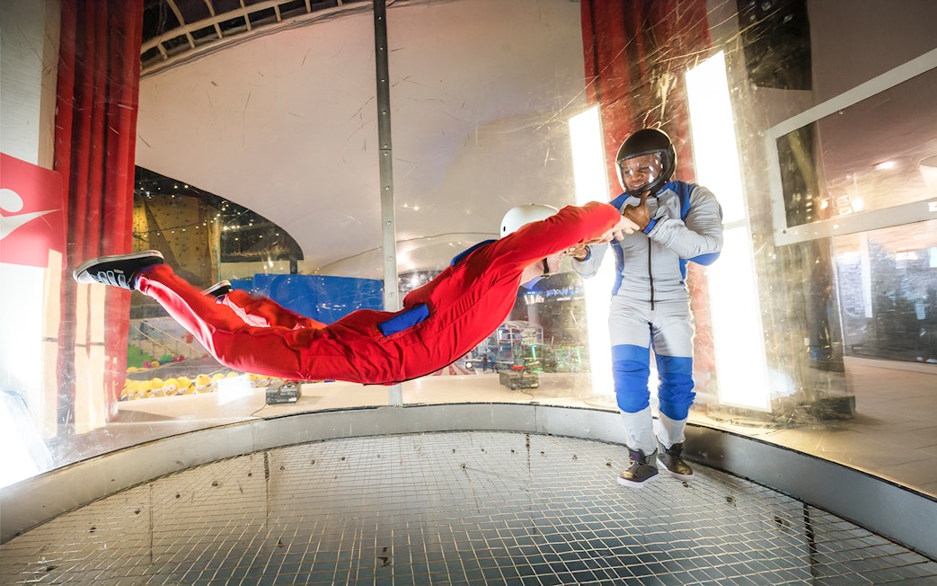 Person skydiving indoors with instructor at iFly Dubai.