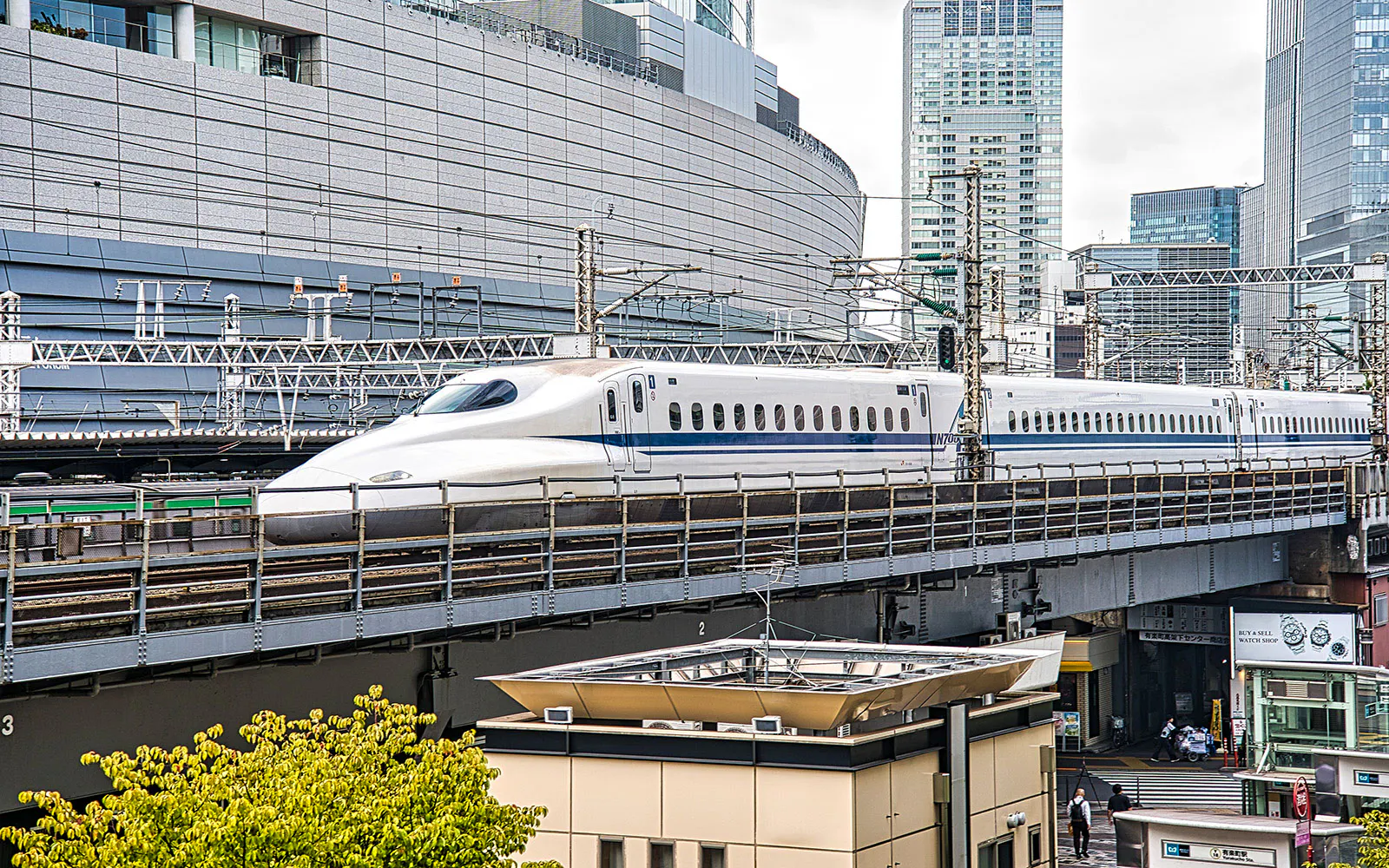 Bullet train traveling through a modern urban landscape with skyscrapers in the background.
