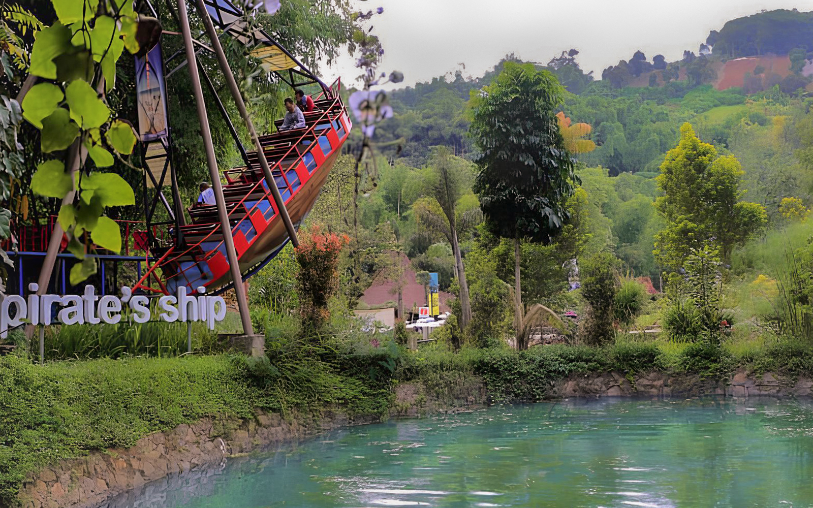 Pirate ship ride at Dago Dreampark with lush greenery and water in Bandung, Indonesia.