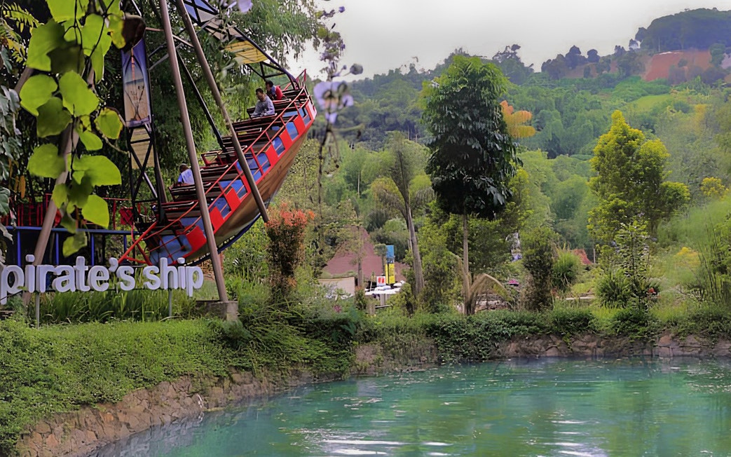 Pirate ship ride at Dago Dreampark with lush greenery and water in Bandung, Indonesia.