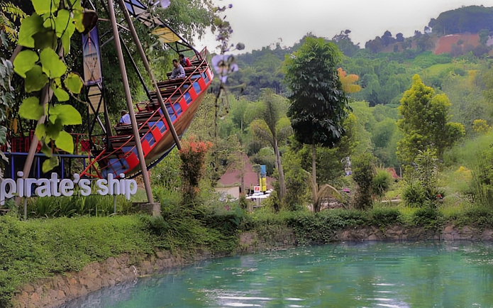 Pirate ship ride at Dago Dreampark with lush greenery and water in Bandung, Indonesia.