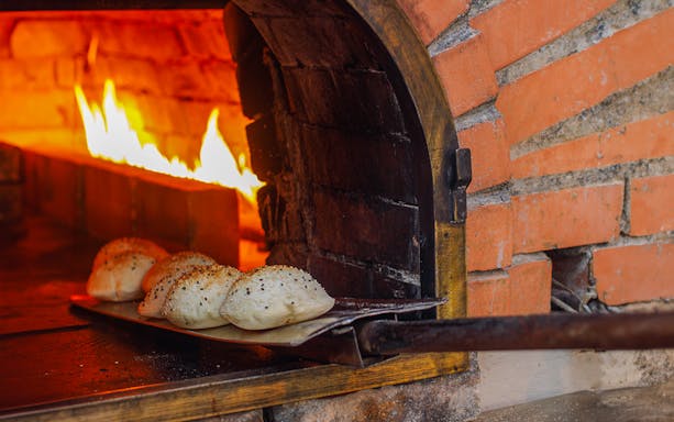 Breads baking in a wood-fired oven at Al Hadheerah Restaurant, Bab Al Shams desert resort.