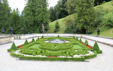 Linderhof Castle gardens with ornate hedges and central fountain.