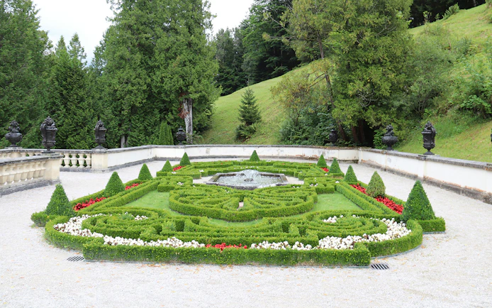 Linderhof Castle gardens with ornate hedges and central fountain.