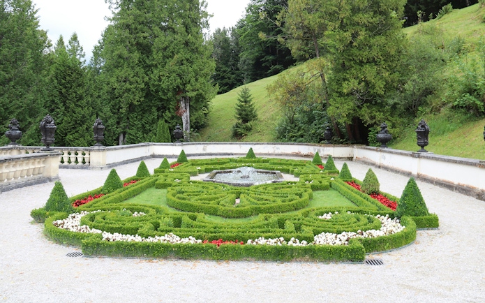Linderhof Castle gardens with ornate hedges and central fountain.