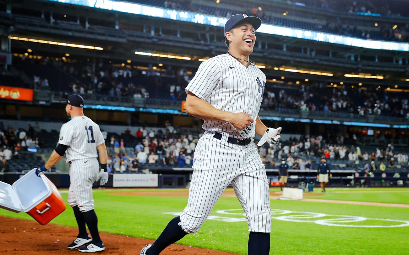 Baseball player in Yankees uniform celebrating on the field at Yankee Stadium.