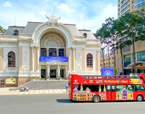 Red double-decker bus in front of Saigon Opera House on Hop-On Hop-Off tour.