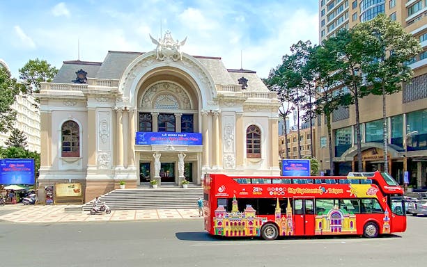 Red double-decker bus in front of Saigon Opera House on Hop-On Hop-Off tour.
