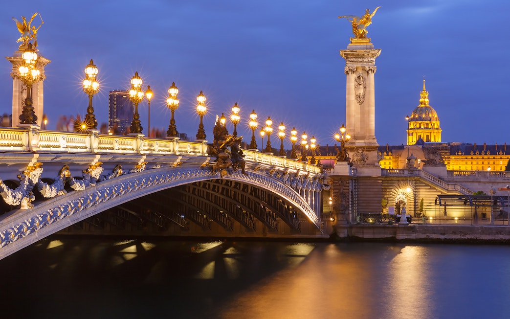 Night view of Pont Alexandre III and Les Invalides along the Seine in Paris, France.