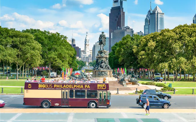 Big Bus tour in Philadelphia passing by the Benjamin Franklin Parkway with city skyline.