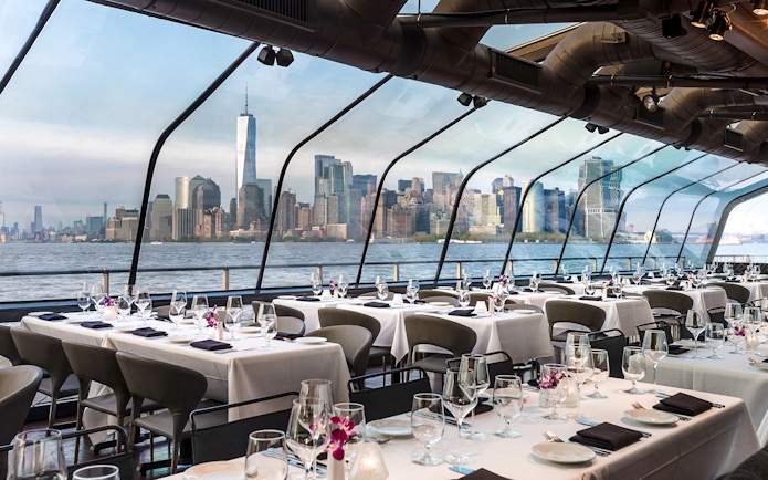 Dining area on Bateaux New York Premier Dinner Cruise with Manhattan skyline view.