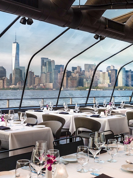 Dining area on Bateaux New York Premier Dinner Cruise with Manhattan skyline view.