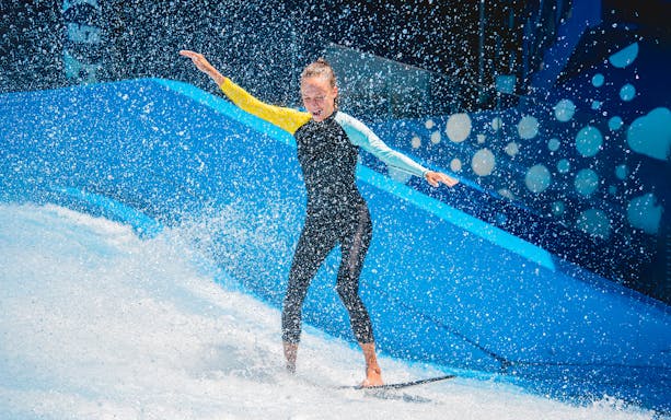 Girl surfing on wave simulator at Waterbom Bali.