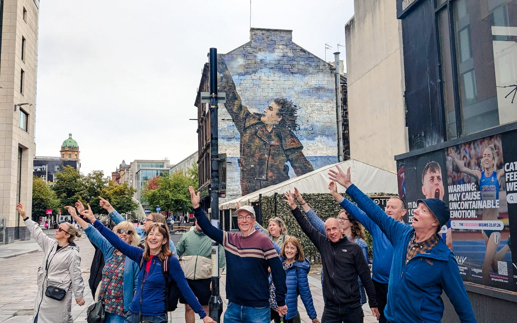 Tourists posing in front of Sir Billy Connolly mural in Glasgow, Scotland.
