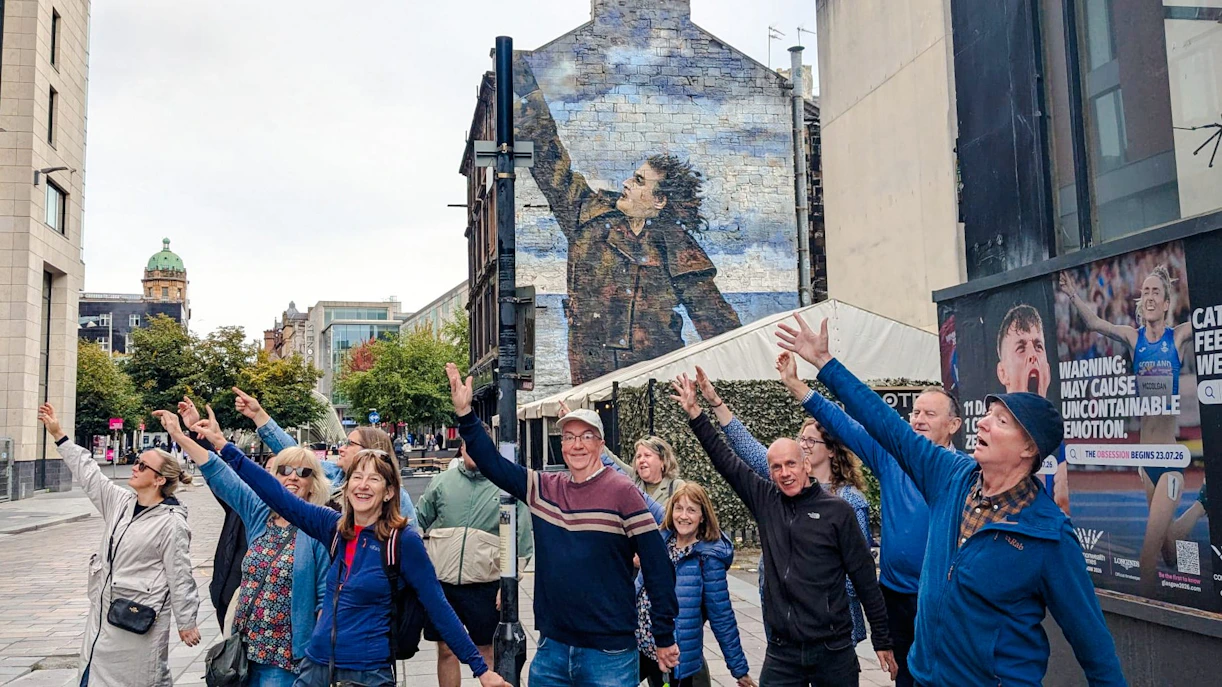 Tourists posing in front of Sir Billy Connolly mural in Glasgow, Scotland.