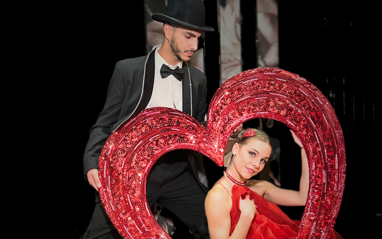 Performers with a heart prop at Saint Valentine's Day Paradis Latin show.
