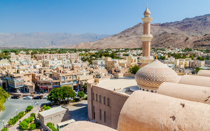 Aerial view of Nizwa with Sultan Qaboos Mosque and surrounding mountains, Oman.