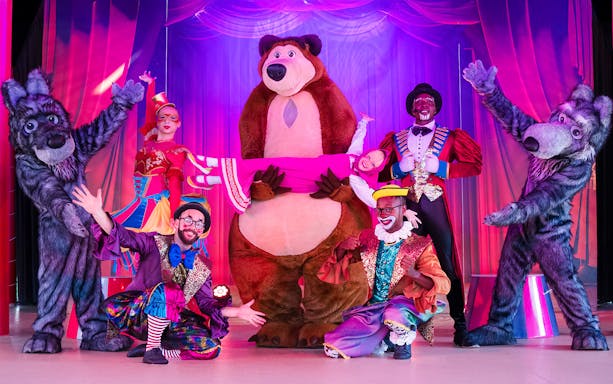 Performers in colorful costumes with a bear mascot at Circus Circus show, Land of Legends, Antalya, Turkey.