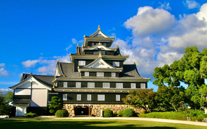 Okayama Castle with traditional architecture under a blue sky in Japan.