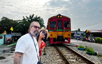 Tourists at Maeklong Railway Market with train approaching, part of Floating Market & Railway Market tour from Laem Chabang.