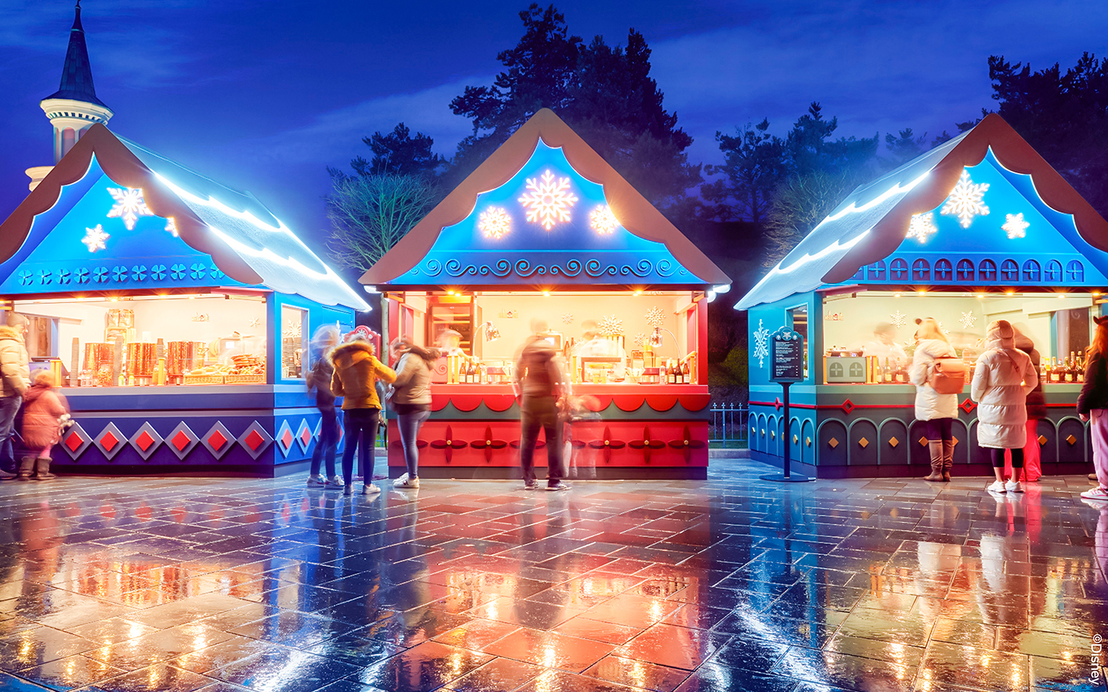 Christmas market stalls at Disneyland Paris 2025 with festive lights and visitors.