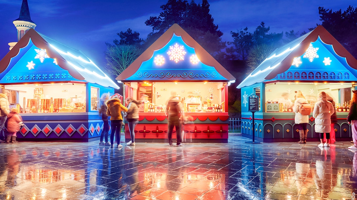 Christmas market stalls at Disneyland Paris 2025 with festive lights and visitors.