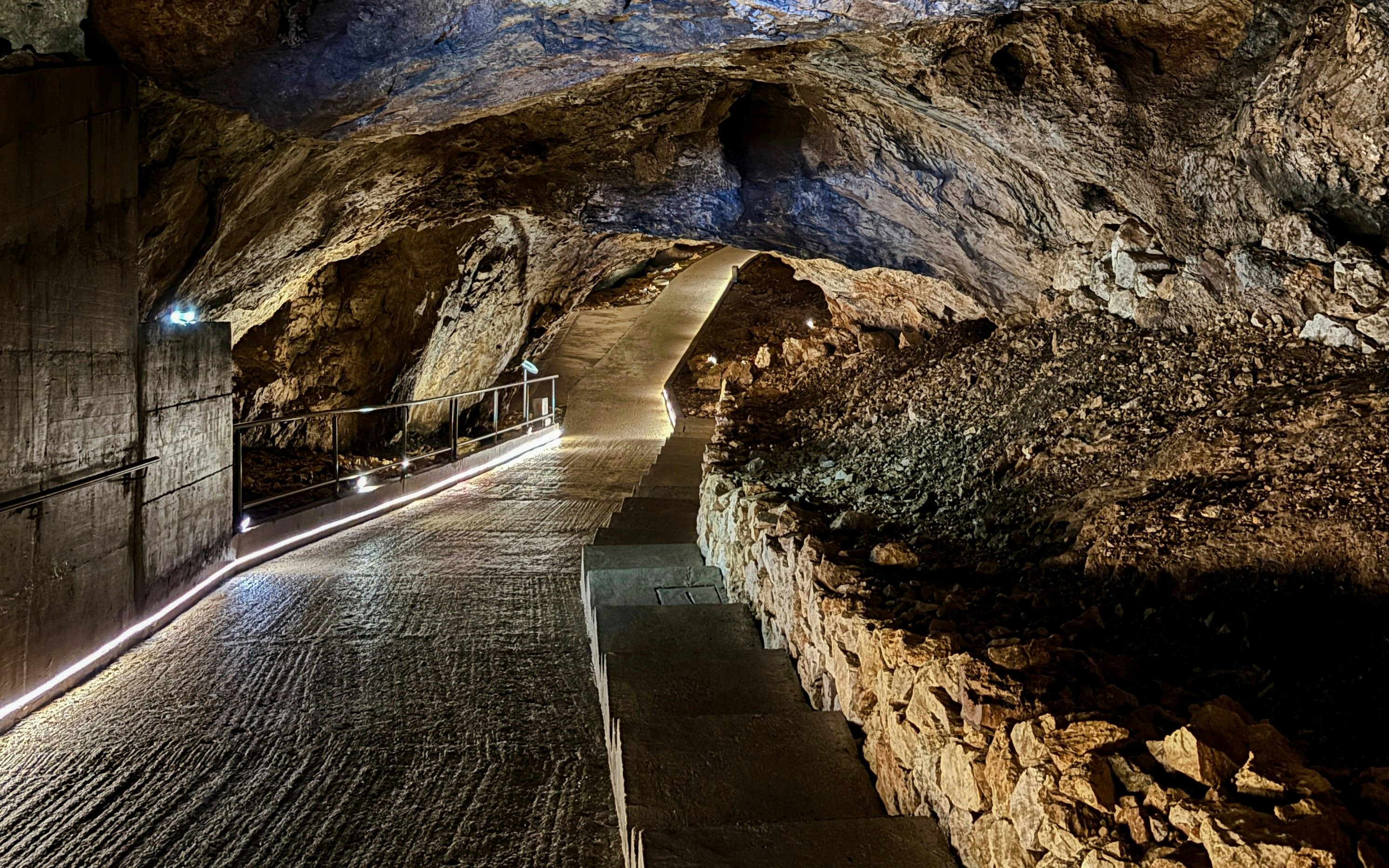 Pathway inside Lipa Cave, Montenegro with illuminated rocky walls and ceiling.