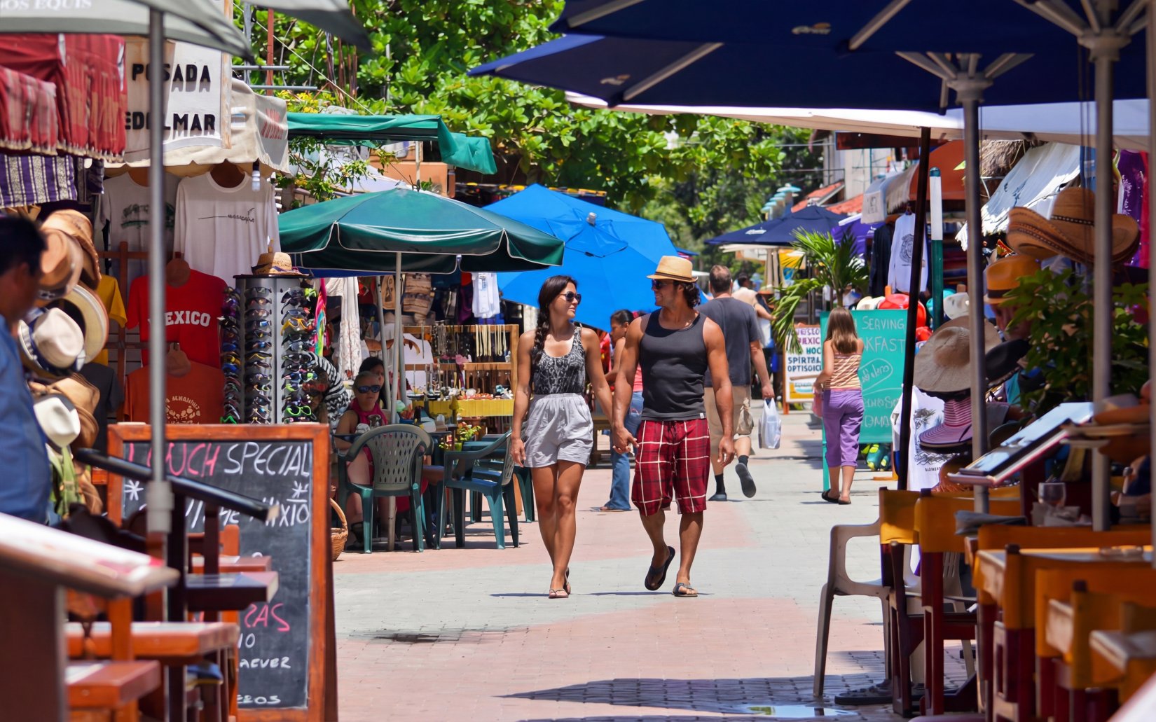 Tourists walking through a vibrant market street in Isla Mujeres island’s main town.