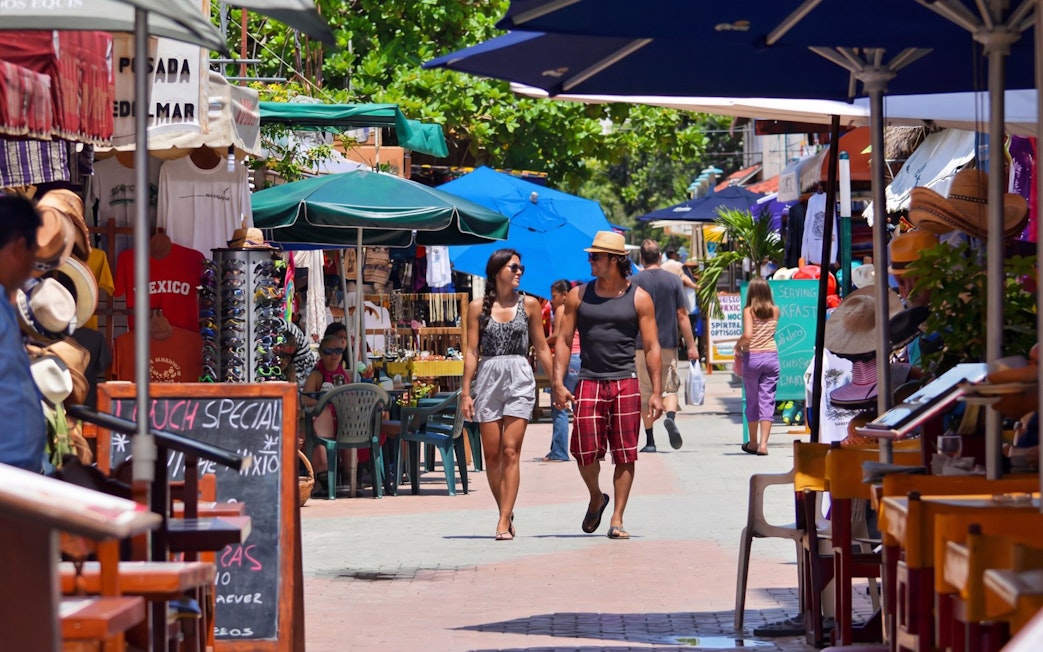 Tourists walking through a vibrant market street in Isla Mujeres island’s main town.