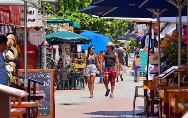 Tourists walking through a vibrant market street in Isla Mujeres island’s main town.