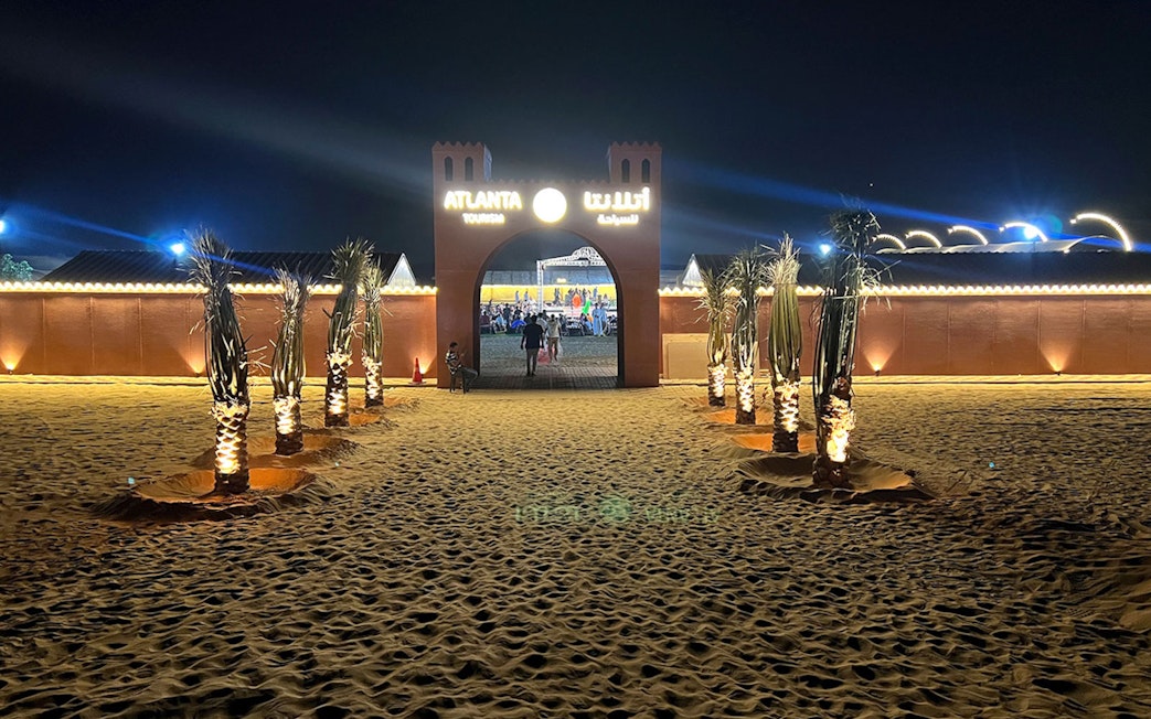 Entrance to Bedouin Desert Camp by Atlanta Tourism at night, with illuminated palm trees.