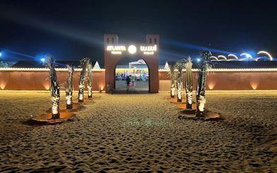 Entrance to Bedouin Desert Camp by Atlanta Tourism at night, with illuminated palm trees.
