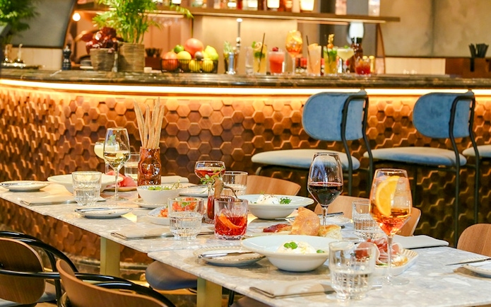 Dinner setting at The Larch, Sky Garden London, with wine glasses and dishes on a marble table.