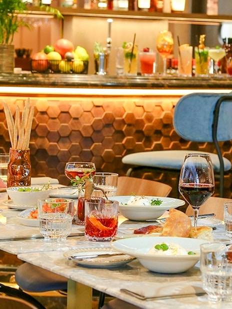 Dinner setting at The Larch, Sky Garden London, with wine glasses and dishes on a marble table.