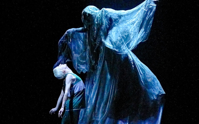 Stage scene from "Harry Potter and the Cursed Child" with a ghostly figure looming over a character.