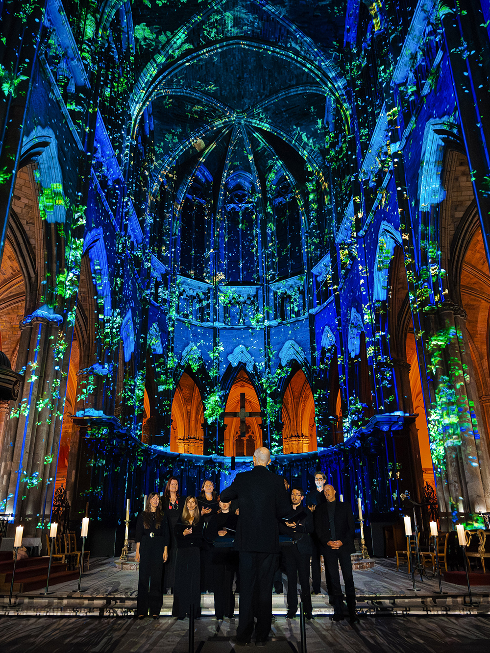 Choir performing under illuminated arches at Manchester Cathedral during LUMINISCENCE 360° show.