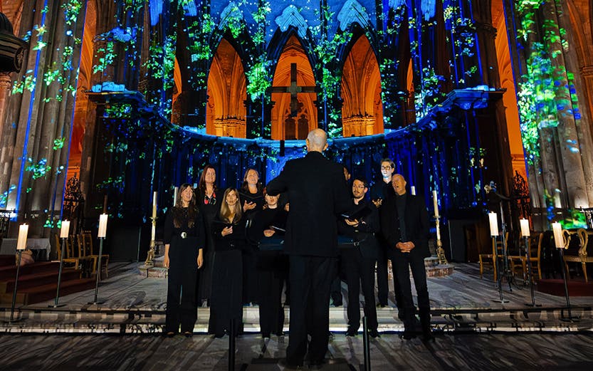 Choir performing under illuminated arches at Manchester Cathedral during LUMINISCENCE 360° show.