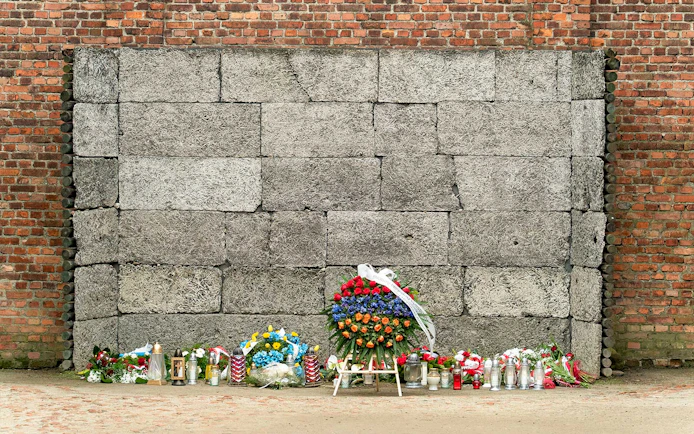 Memorial wall with flowers and candles at Auschwitz concentration camp.