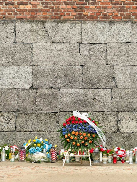 Memorial wall with flowers and candles at Auschwitz concentration camp.
