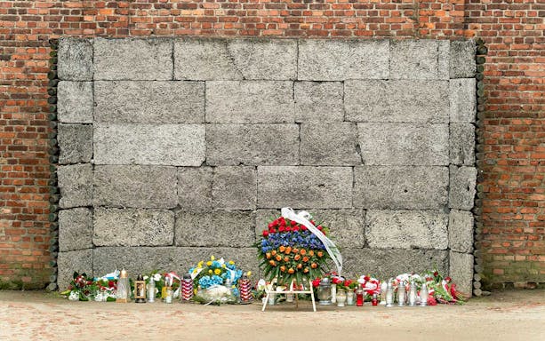 Memorial wall with flowers and candles at Auschwitz concentration camp.