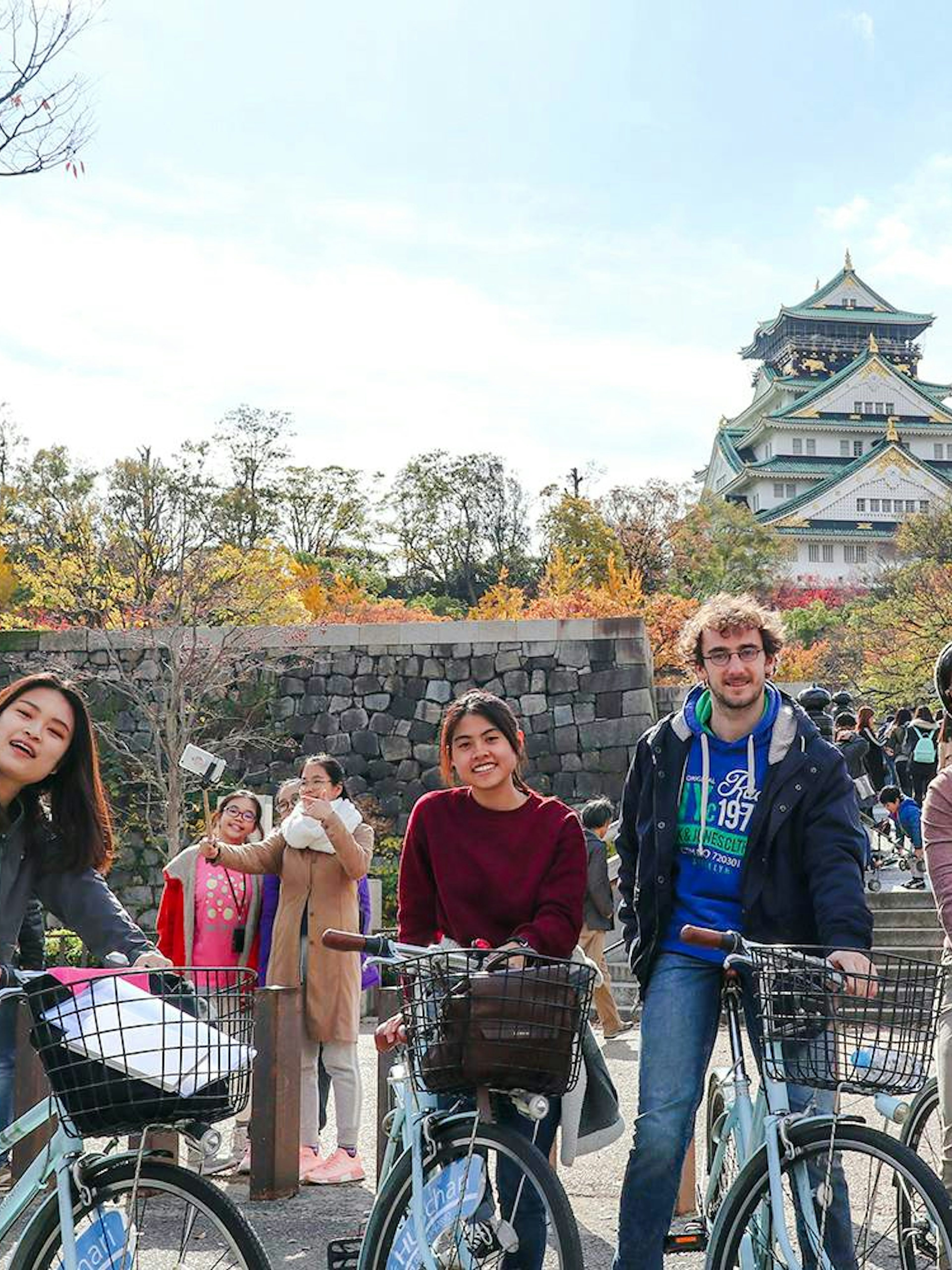 Tourists with bicycles in front of Osaka Castle, Japan.