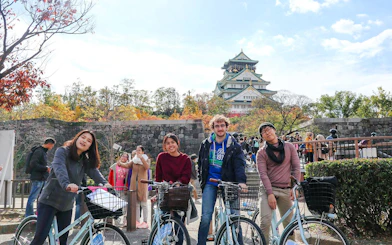 Tourists with bicycles in front of Osaka Castle, Japan.